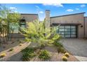 Modern home exterior with desert landscaping, a stone accent wall, and a garage with glass panel door at 12315 E Black Rock Rd, Scottsdale, AZ 85255