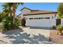 Attached two-car garage with a white door and tile roof, surrounded by lush landscaping and a concrete driveway at 16014 S 13Th Way, Phoenix, AZ 85048