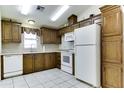 Efficient kitchen featuring wooden cabinets, white appliances, and tiled flooring at 17200 W Bell Rd # 1551, Surprise, AZ 85374