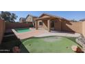 Backyard with a covered patio, a pool, desert landscaping, and a putting green at 22583 W Lasso Ln, Buckeye, AZ 85326