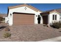 Beautiful home featuring a brick driveway, desert landscaping, and a two-car garage at 5668 N 206Th N Ln, Buckeye, AZ 85396