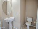 Cozy bathroom with pedestal sink, oval mirror, and toilet at 8613 S 49Th Dr, Laveen, AZ 85339