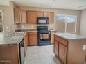 Well-lit kitchen with tile floor, wooden cabinets, black appliances, sink, and island at 8613 S 49Th Dr, Laveen, AZ 85339