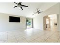 Bright living room featuring tile flooring, neutral paint, ceiling fans, and large sliding glass doors at 1723 E Behrend Dr, Phoenix, AZ 85024