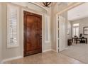 Elegant foyer featuring a beautiful wood door, shuttered windows, and tile flooring at 42429 N Cross Timbers Ct, Anthem, AZ 85086