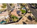 Aerial view of a home featuring solar panels, a green backyard with a pool, and an outdoor living space at 4702 N 151St Dr, Goodyear, AZ 85395