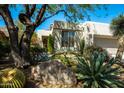 Charming desert home featuring barrel cactus, desert landscaping, and an attached two-car garage at 7016 E Stone Raven Trl, Scottsdale, AZ 85266