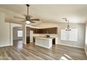 Open-concept kitchen with a center island, dark wood cabinetry, stainless steel appliances, and wood flooring at 7259 W Tina Ln, Glendale, AZ 85310