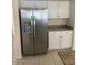 Kitchen view showcasing a modern stainless steel refrigerator, white cabinets, and granite counters at 7728 W Via Montoya Dr, Peoria, AZ 85383