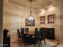 Well-lit dining room with a decorative chandelier, artwork, and a view of the outdoor living space at 8928 E Wethersfield Rd, Scottsdale, AZ 85260