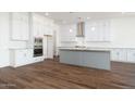 A spacious kitchen featuring white cabinets, modern appliances, a central island, and wood-look tile flooring at 9907 S 37Th Dr, Laveen, AZ 85339