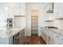 Modern kitchen featuring stainless steel appliances, a pantry, and ample storage space with white cabinets at 9907 S 37Th Dr, Laveen, AZ 85339