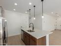 Bright kitchen island illuminated by pendant lights, showcasing stainless steel appliances and sleek white countertops at 11627 W Beck Ave, Youngtown, AZ 85363