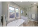 Bright bathroom featuring a freestanding tub under a window and a glass-enclosed shower with marble details at 1520 E Elmwood Cir, Mesa, AZ 85203