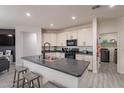 The kitchen has white cabinets, stainless steel appliances, an island with seating, and wood-look flooring at 7552 W Darrel Rd, Laveen, AZ 85339