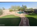 A backyard with green turf, a pool and spa, desert landscaping, and a stone walkway at 8662 W Paradise Ln, Peoria, AZ 85382