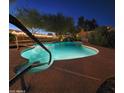 Illuminated pool and spa with a waterfall feature at twilight, surrounded by desert landscaping at 8662 W Paradise Ln, Peoria, AZ 85382