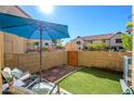 Private backyard featuring artificial turf, a blue umbrella, and a wooden fence, perfect for outdoor relaxation at 921 W University Dr # 1143, Mesa, AZ 85201
