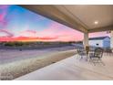 Covered back patio with outdoor seating overlooks the expansive backyard and desert landscape at 28211 N Quintana Pl, Queen Creek, AZ 85144