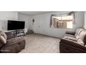 Well-lit living room with tile floors, two plush sofas, and a TV at 4615 E Southgate Ave, Phoenix, AZ 85040