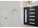 Bright entryway featuring a modern black door with sidelights and an art niche on the adjacent wall at 5704 E Estrid Ave, Scottsdale, AZ 85254