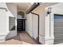 Close up of entry way with textured stucco, black rain gutters, and an arched transom window above door at 5704 E Estrid Ave, Scottsdale, AZ 85254