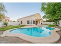 Backyard with a refreshing blue pool, lush lawn, and covered patio, perfect for outdoor living at 62 N Amber Ct, Chandler, AZ 85225