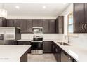 Close-up of kitchen with stainless steel appliances, white countertops, and modern dark cabinetry at 11615 W Beck Ave, Youngtown, AZ 85363