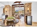 Open-concept living room featuring stone pillars, wood-beamed ceilings, and a cozy fireplace at 14475 E Cortez Dr, Scottsdale, AZ 85259