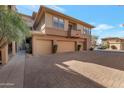 Exterior view of tan townhome featuring two car garage and lush landscaping at 19777 N 76Th St # 2150, Scottsdale, AZ 85255