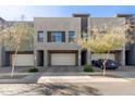 Modern townhome exterior featuring three garages with gray stucco and desert landscaping at 25318 N 19Th Dr, Phoenix, AZ 85085