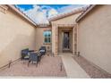Inviting front patio with comfortable seating, a decorative front door, and tasteful desert landscaping details at 41553 W Springtime Rd, Maricopa, AZ 85138