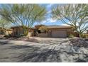 Stunning single-story home featuring a three-car garage, desert landscaping and mature trees at 42211 N Long Cove Way, Anthem, AZ 85086