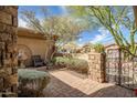 Landscaped entry to the home with brick walkway, wrought iron gate and stone column at 42211 N Long Cove Way, Anthem, AZ 85086