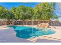 Lush backyard featuring a sparkling pool with rock waterfall, surrounded by mature trees for privacy and shade at 528 N Nevada Way, Gilbert, AZ 85233