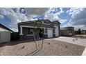 Charming single-story home with a two-car garage, desert landscaping, and a young tree in the front yard at 15769 W Cheryl Dr, Waddell, AZ 85355
