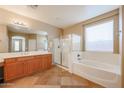 A bathroom featuring a soaking tub, glass shower, and a double sink vanity at 18457 W Ivy Ln, Surprise, AZ 85388