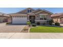 Charming single-story home with well-manicured lawn and brick-paved driveway leading to an attached two-car garage at 20729 E Canary Way, Queen Creek, AZ 85142