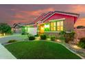 Beautiful single-story home with lush landscaping and brick accents, illuminated by decorative lights at twilight at 20729 E Canary Way, Queen Creek, AZ 85142