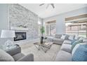 Bright living room featuring a stone fireplace, a ceiling fan, and neutral-colored decor at 3138 W Ravina Ln, Anthem, AZ 85086