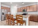 Open concept kitchen with granite countertops, wood cabinets, stainless appliances, and breakfast bar seating at 35751 N Bandolier Dr, San Tan Valley, AZ 85144