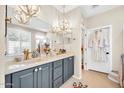 Elegant bathroom with double vanity, chandeliers, and walk-in closet at 41229 N Belfair Way, Anthem, AZ 85086