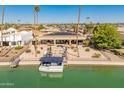 Back exterior boasts covered patio, green space, lounge furniture and private dock with boat at 9945 W Cameo Dr, Sun City, AZ 85351