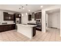 Modern kitchen with dark wood cabinets, a white island, stainless steel appliances, and pendant lighting at 17462 W Straight Arrow Ln, Surprise, AZ 85387