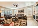 Comfortable living room featuring neutral tones, plush seating, a ceiling fan, and large windows at 26828 W Piute Ave, Buckeye, AZ 85396