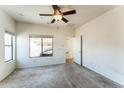 Bright, spacious bedroom with carpet, ceiling fan, and natural light from a large window at 44922 W Alamendras St, Maricopa, AZ 85139