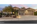Desert home features a two-car garage, xeriscaped yard, and warm exterior lighting at 5892 E Evening Glow Dr, Scottsdale, AZ 85266