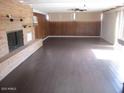 Spacious living room with a brick fireplace, wood-look floors and wood paneling at 8219 N 59Th Ave, Glendale, AZ 85302