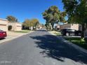 Quiet neighborhood street featuring well-maintained homes, green lawns and mature shade trees on a bright, sunny day at 19224 N 93Rd Ave, Peoria, AZ 85382
