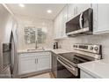 Modern kitchen with stainless steel appliances, white cabinets, tile backsplash, and a bright window at 19400 N Westbrook Pkwy # 241, Peoria, AZ 85382